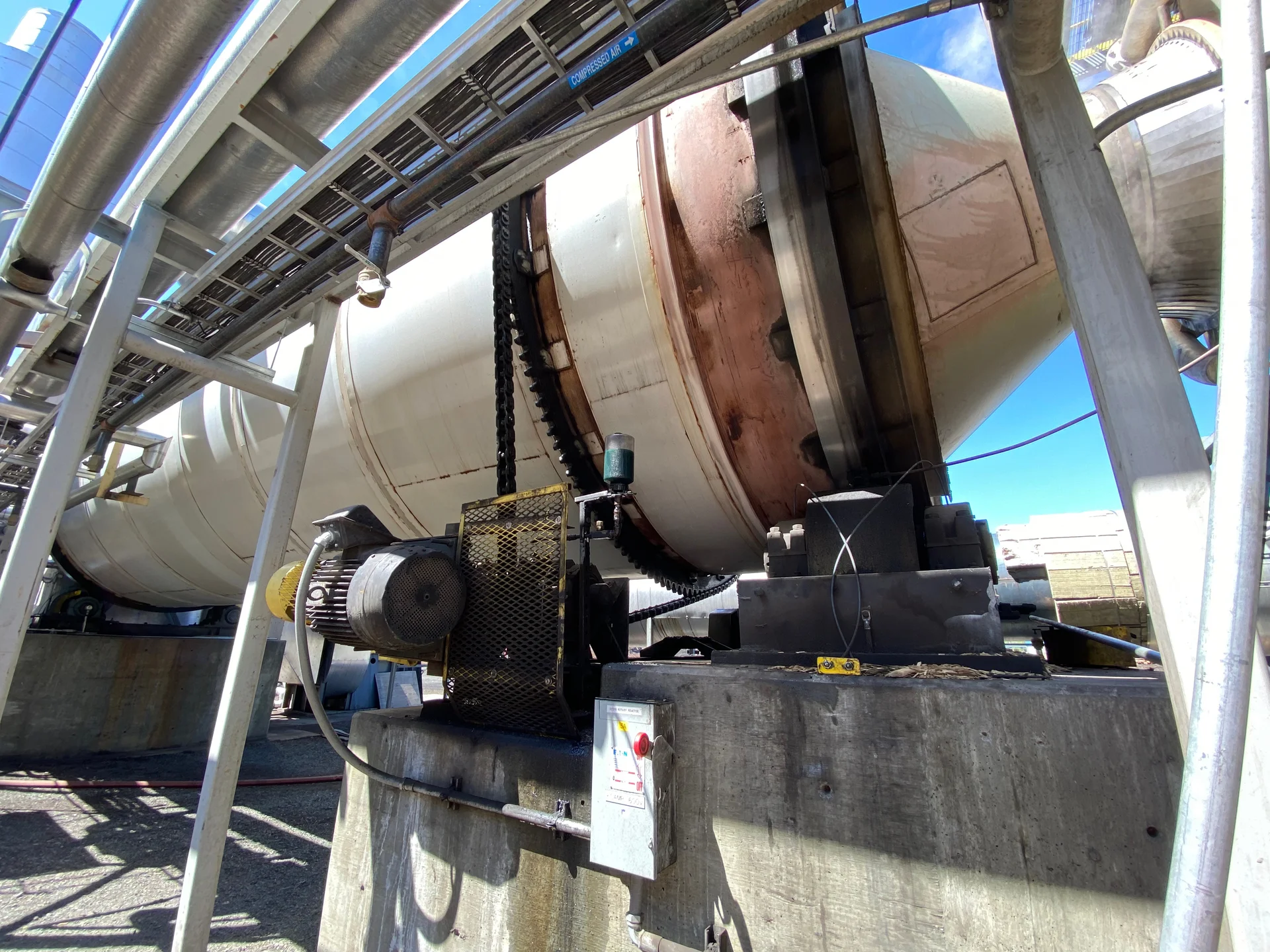 Reactor de tambor rotativo con cadena de transmisión, motor y rodillos de apoyo.